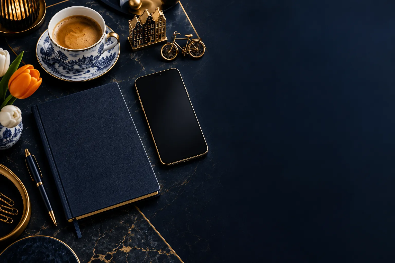 Luxurious overhead view of a dark navy workspace with a notebook, smartphone, and coffee cup with gold accents and Dutch edit